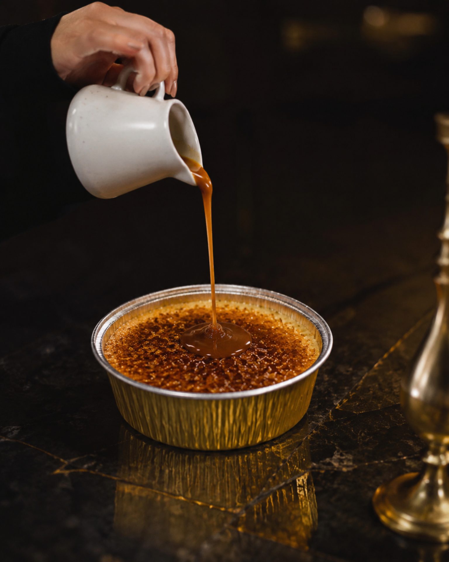 Caramel being poured over a golden crème caramel flan